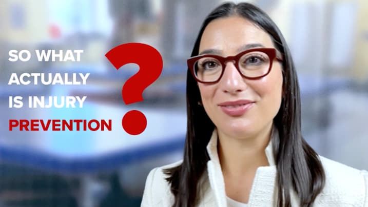 A woman with long dark hair and glasses smiles at the camera. She is wearing a white jacket. The background is blurred, and the text reads, 